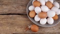 White and brown eggs in plate and one egg next to a small feather on an old wooden desk, place for text Royalty Free Stock Photo