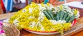 Many white chamomile flowers and yellow acacia flowers bouquets wrapped in cones, made by folded banana leaves, are prepared for