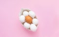 Many white eggs and one brown egg in a white dish on a pink background. Easter. Top view Royalty Free Stock Photo
