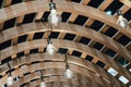 Many White Light Bulbs are hung on the Ceiling of the Wooden Curved Pergola Structure