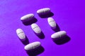 Many white medical pills in a row on a pink background. pills cast a shadow.  pill pattern. Royalty Free Stock Photo