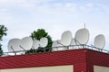 Many white parabolic satellite antena dishes on the roof of the house Royalty Free Stock Photo