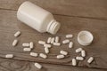 Many white pills with bottle on wooden table Royalty Free Stock Photo