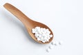 Many white pills on wooden spoon on white background. top view Royalty Free Stock Photo