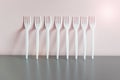 White plastic forks standing in row on gray reflective surface next to yellow wal Royalty Free Stock Photo