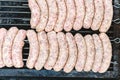 Many white sausages in a row to roast on a barbecue with charcoal Royalty Free Stock Photo