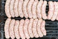 Many white sausages in a row to roast on a barbecue with charcoal Royalty Free Stock Photo