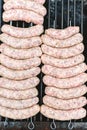 Many white sausages in a row to roast on a barbecue with charcoal Royalty Free Stock Photo