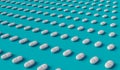 Many white tablets arranged in diagonal lines on blue background