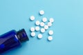 Many white tablets spilling out of package, Close up pills spilling out of pill bottle on blue background. Medicine, medical Royalty Free Stock Photo