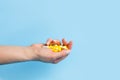 Many white and yellow pills in woman hand on blue background. Medical concept of medicine treatment, vitamins Royalty Free Stock Photo