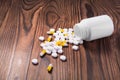 Many white and yellow tablets and drug bottle on a dark background. Many pills are scattered on a wooden table. Suicide. Royalty Free Stock Photo