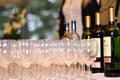 Many wine glasses in rows and different wine bottles on a table with a white tablecloth. Restaurant setting or an event like drink Royalty Free Stock Photo