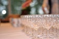 Many wine glasses in rows on a table with a white tablecloth. Restaurant setting or an event like drink or wine tasting. Bokeh Royalty Free Stock Photo