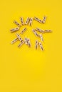 Many wooden clothespins on a yellow background, as a substrate pin clothes peg