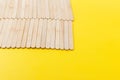 Many wooden ice cream sticks in row on yellow background in corner, flat lay Royalty Free Stock Photo