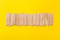 Many wooden ice cream sticks in row on yellow background, flat lay Royalty Free Stock Photo