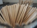 Many wooden stirrers in container.