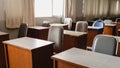 Many wooden tables and chairs well arranged in the university classroom but no student. Empty classroom with no student due to Royalty Free Stock Photo
