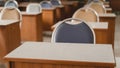 Many wooden tables and chairs well arranged in the university classroom but no student. Empty classroom with no student due to Royalty Free Stock Photo