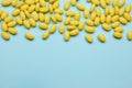 Many yellow dragee candies on light blue background, flat lay. Space for text Royalty Free Stock Photo