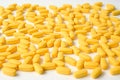 Many yellow health vitamin drug medication tablets lying on white surface