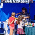 Maori fried bread being prepared for two young customers by a cheerful market stall holder, New Zealand