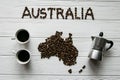 Map of the Australia made of roasted coffee beans laying on white wooden textured background with coffee maker and two coffee cups Royalty Free Stock Photo