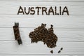 Map of the Australia made of roasted coffee beans laying on white wooden textured background with toy train Royalty Free Stock Photo