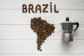 Map of the Brazil made of roasted coffee beans laying on white wooden textured background with coffee maker Royalty Free Stock Photo