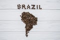 Map of the Brazil made of roasted coffee beans laying on white wooden textured background