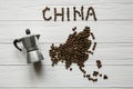 Map of the China made of roasted coffee beans laying on white wooden textured background with coffee maker Royalty Free Stock Photo