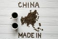 Map of the China made of roasted coffee beans laying on white wooden textured background cups of coffee Royalty Free Stock Photo