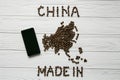 Map of the China made of roasted coffee beans laying on white wooden textured background with phone Royalty Free Stock Photo