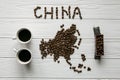 Map of the China made of roasted coffee beans laying on white wooden textured background with toy train and two cups of coffee Royalty Free Stock Photo