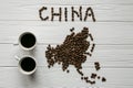 Map of the China made of roasted coffee beans laying on white wooden textured background with two cups of coffee Royalty Free Stock Photo