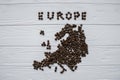 Map of the Europe made of roasted coffee beans laying on white wooden textured background with cup of coffee Royalty Free Stock Photo