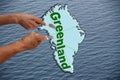 Map of Greenland cut and divided by three hands with forks on a background of blue water, collage, close-up, copy space Royalty Free Stock Photo