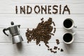 Map of the Indonesia made of roasted coffee beans laying on white wooden textured background with cups of coffee and coffee maker Royalty Free Stock Photo