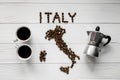 Map of the Italy made of roasted coffee beans laying on white wooden textured background with two cups and coffee maker Royalty Free Stock Photo