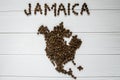 Map of the Jamaica made of roasted coffee beans laying on white wooden textured background