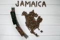 Map of the Jamaica made of roasted coffee beans laying on white wooden textured background with toy train