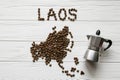 Map of the Laos made of roasted coffee beans laying on white wooden textured background with coffee maker Royalty Free Stock Photo