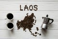 Map of the Laos made of roasted coffee beans laying on white wooden textured background with coffee maker and two cups of coffee Royalty Free Stock Photo