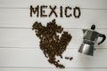 Map of the Mexico made of roasted coffee beans laying on white wooden textured background with coffee maker Royalty Free Stock Photo
