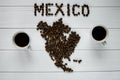 Map of the Mexico made of roasted coffee beans laying on white wooden textured background with two cups of coffee Royalty Free Stock Photo