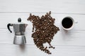 Map of the North America made of roasted coffee beans laying on white wooden textured background with cup of coffee, coffee maker Royalty Free Stock Photo