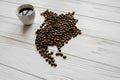 Map of the North America made of roasted coffee beans laying on white wooden textured background with cup of coffee Royalty Free Stock Photo
