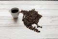 Map of the North America made of roasted coffee beans laying on white wooden textured background with cup of coffee Royalty Free Stock Photo