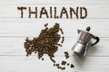 Map of the Thailand made of roasted coffee beans laying on white wooden textured background with coffee maker Royalty Free Stock Photo